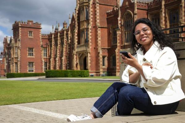 international student sitting outside the main building of Queen's University Belfast